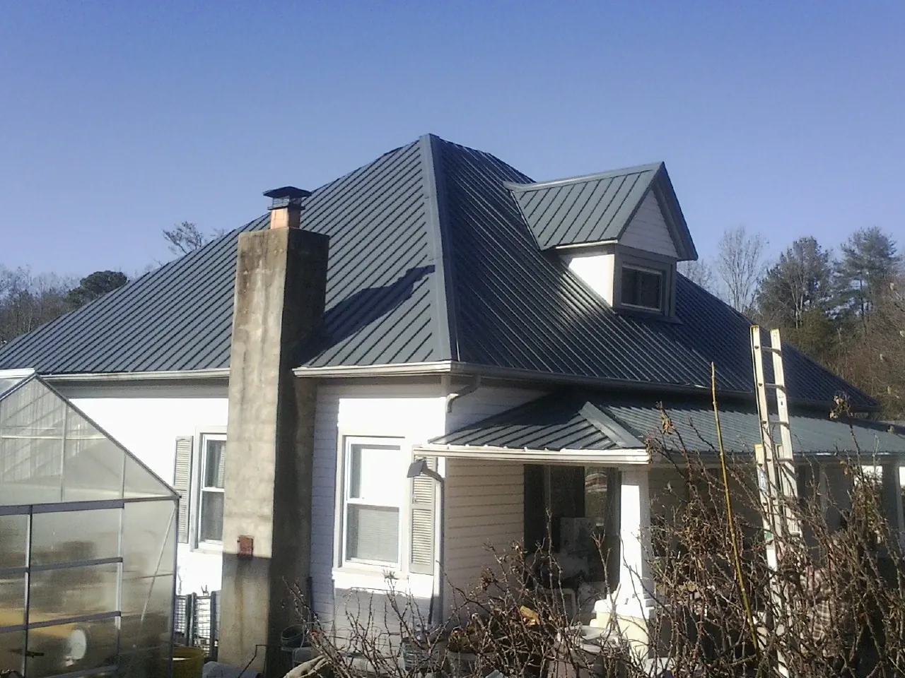 Dark blue standing seam metal roof on a white farmhouse with dormer — Slate & Tile Roof Repair by Roofing Brothers in Pewee Valley