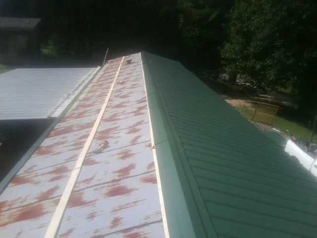 Old rusted panels beside newly installed green metal roofing — Wind Damage Roof Repair by Roofing Brothers in Pewee Valley