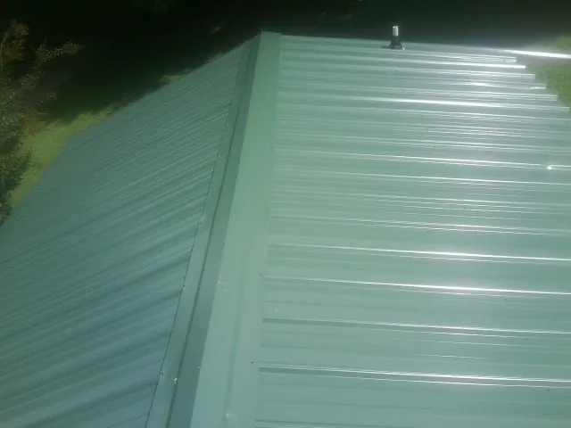 New green metal panels meeting at the ridge of a roof — Flat Roof Repair work by our crew in Pewee Valley
