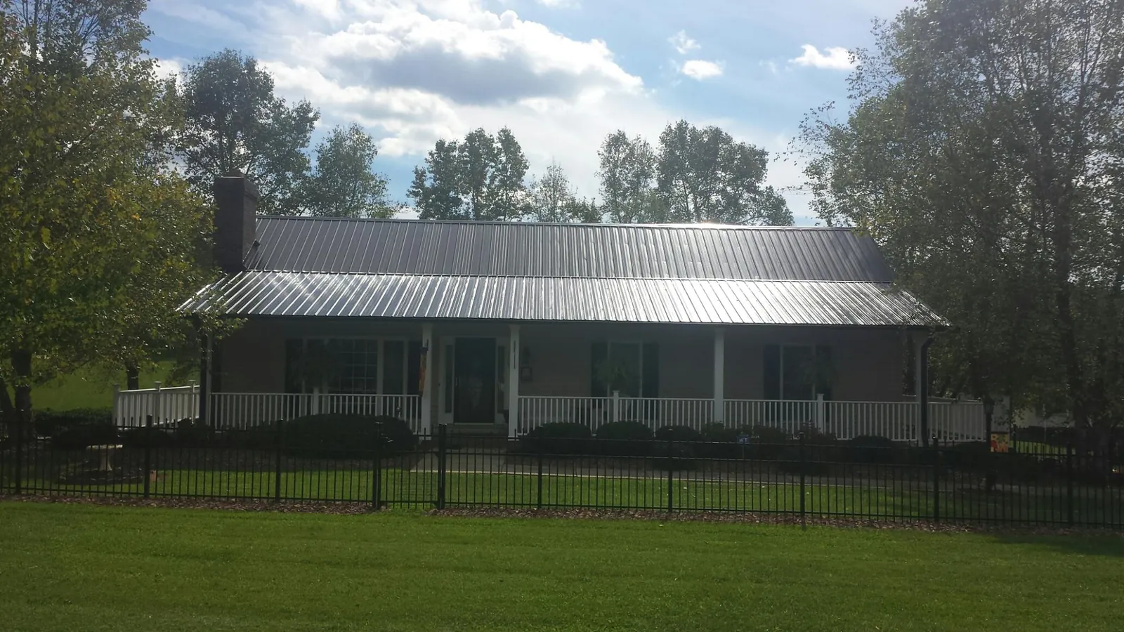 Gray metal roof on a brick ranch with a full width front porch — Gutter Guard Installation work by our crew in Pewee Valley
