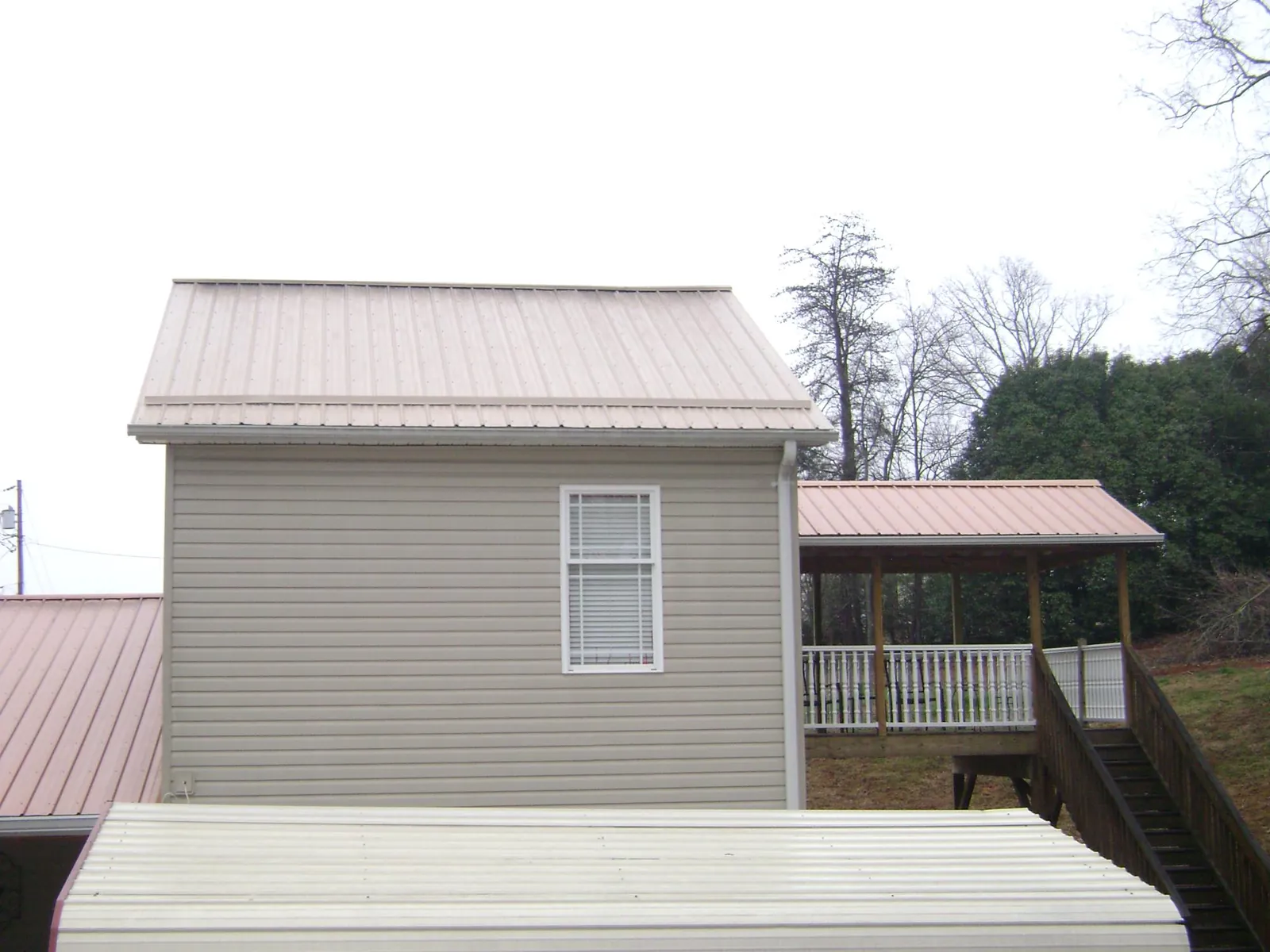 Tan metal roofs on a two story addition and attached porch, from a Roof Replacement job in Pewee Valley