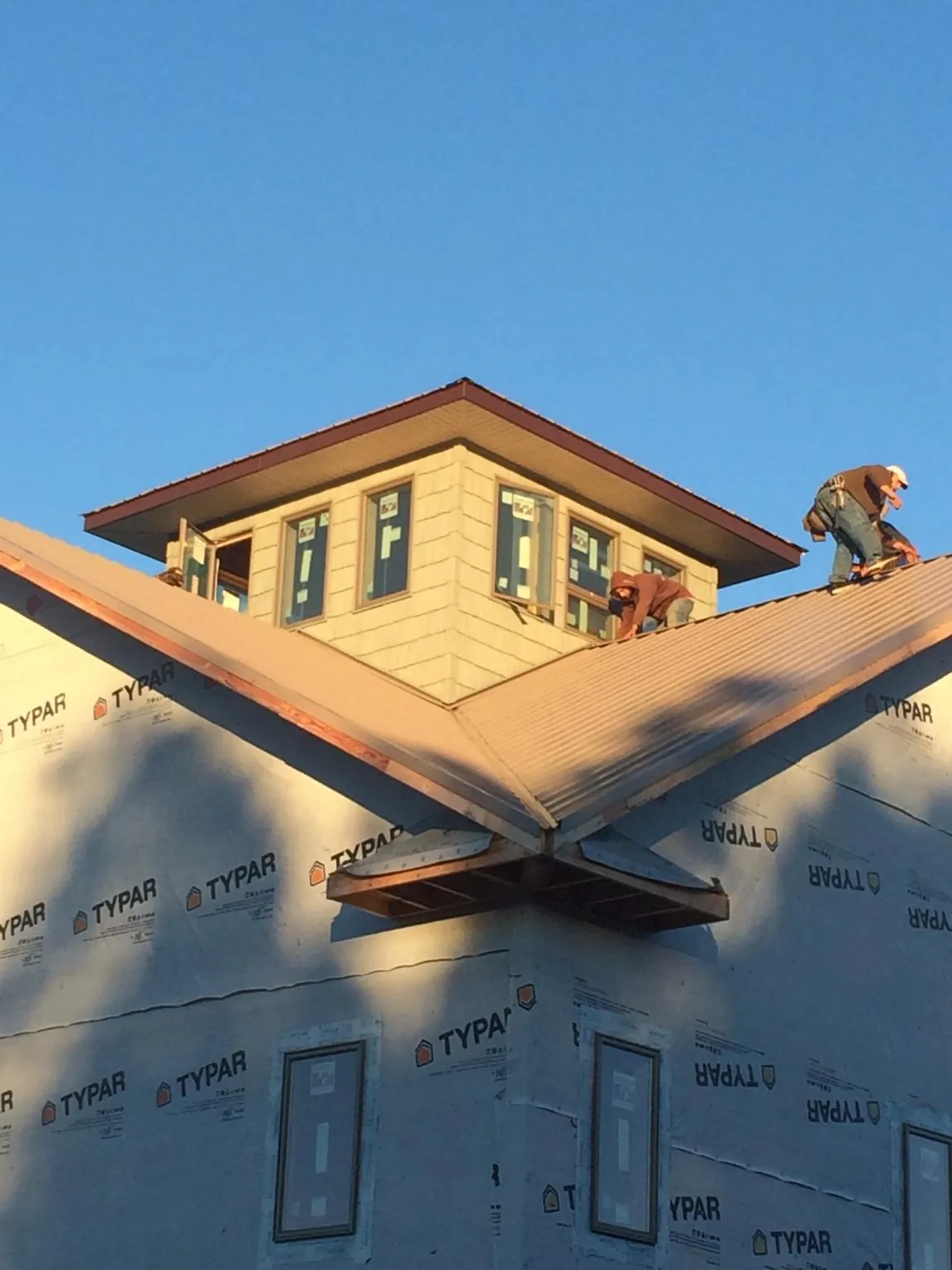 Roofers working around a rooftop cupola on a new metal roof at sunset — Roof Waterproofing in Pewee Valley by Roofing Brothers